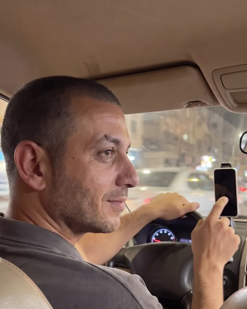 A smiling captain in his car pointing at his phone on the mount